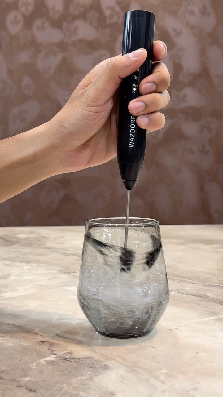 Small Kitchen Essentials: 13 Tools That Actually Matter 12 Hand using a black electric milk frother to mix liquid in a glass.