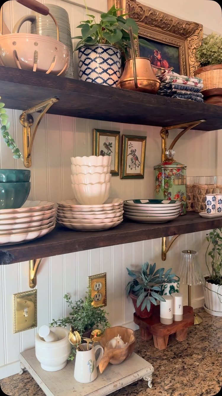 32 Simply Kitchen Design Ideas for a Clean, Modern Space 2 Dark wood open shelves with gold brackets holding ceramics and plants on white walls.