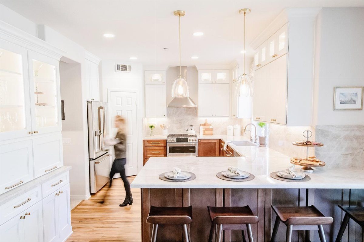 32 Simply Kitchen Design Ideas for a Clean, Modern Space 16 White marble kitchen peninsula with dark wooden stools in a bright, modern kitchen.