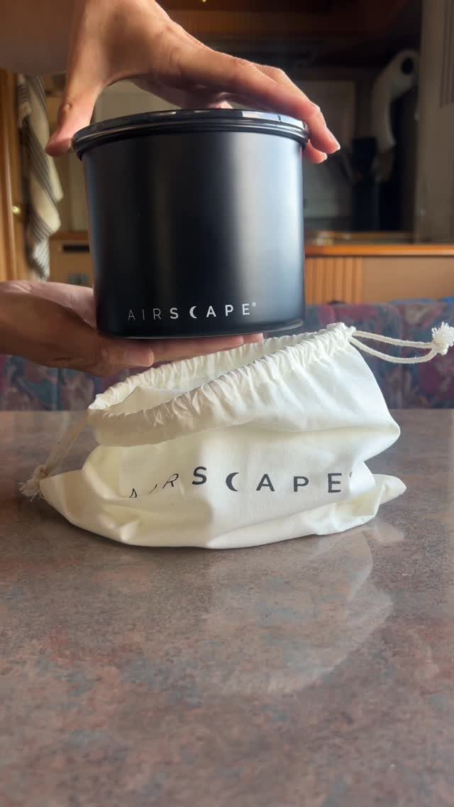 10 Kitchen Storage Container Ideas for Pantry and Fridge 6 Matte black Airscape canister held above a white branded fabric drawstring storage pouch.
