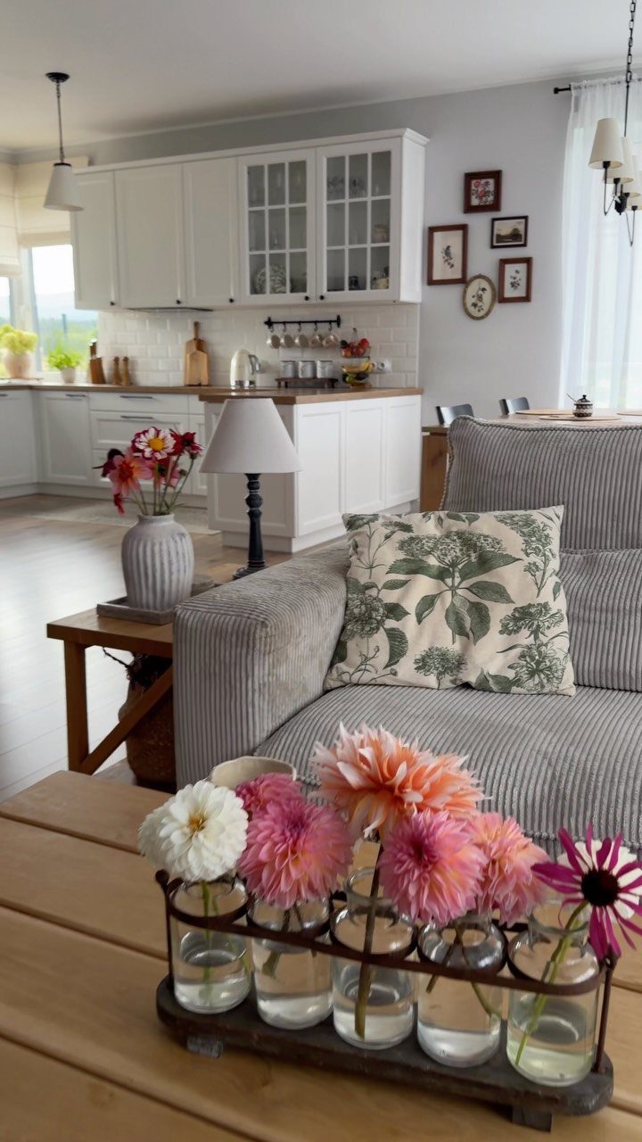 White kitchen cabinets and walls in an open living area with a grey sofa.