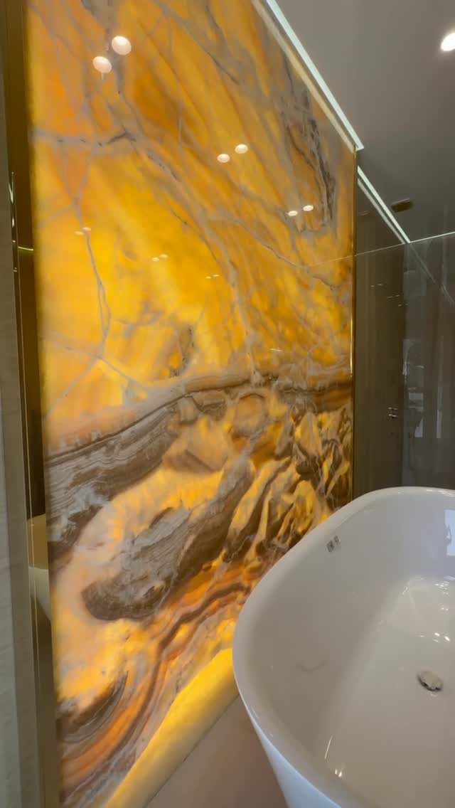 Bathroom Alcove Ideas: 29 Designs for Tubs, Showers & More 25 Backlit yellow onyx stone wall panel behind a white freestanding bathtub in a bathroom.