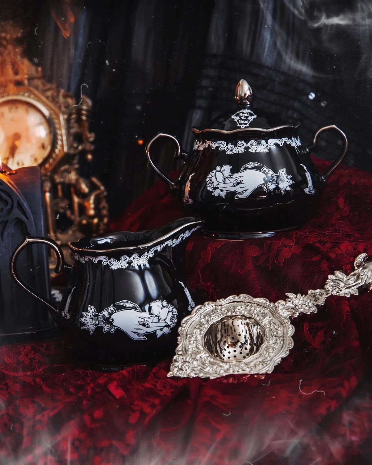 Gothic Tea Set: 24 Dark & Elegant Serving Ideas 17 Black porcelain tea set with white floral patterns on red velvet fabric.