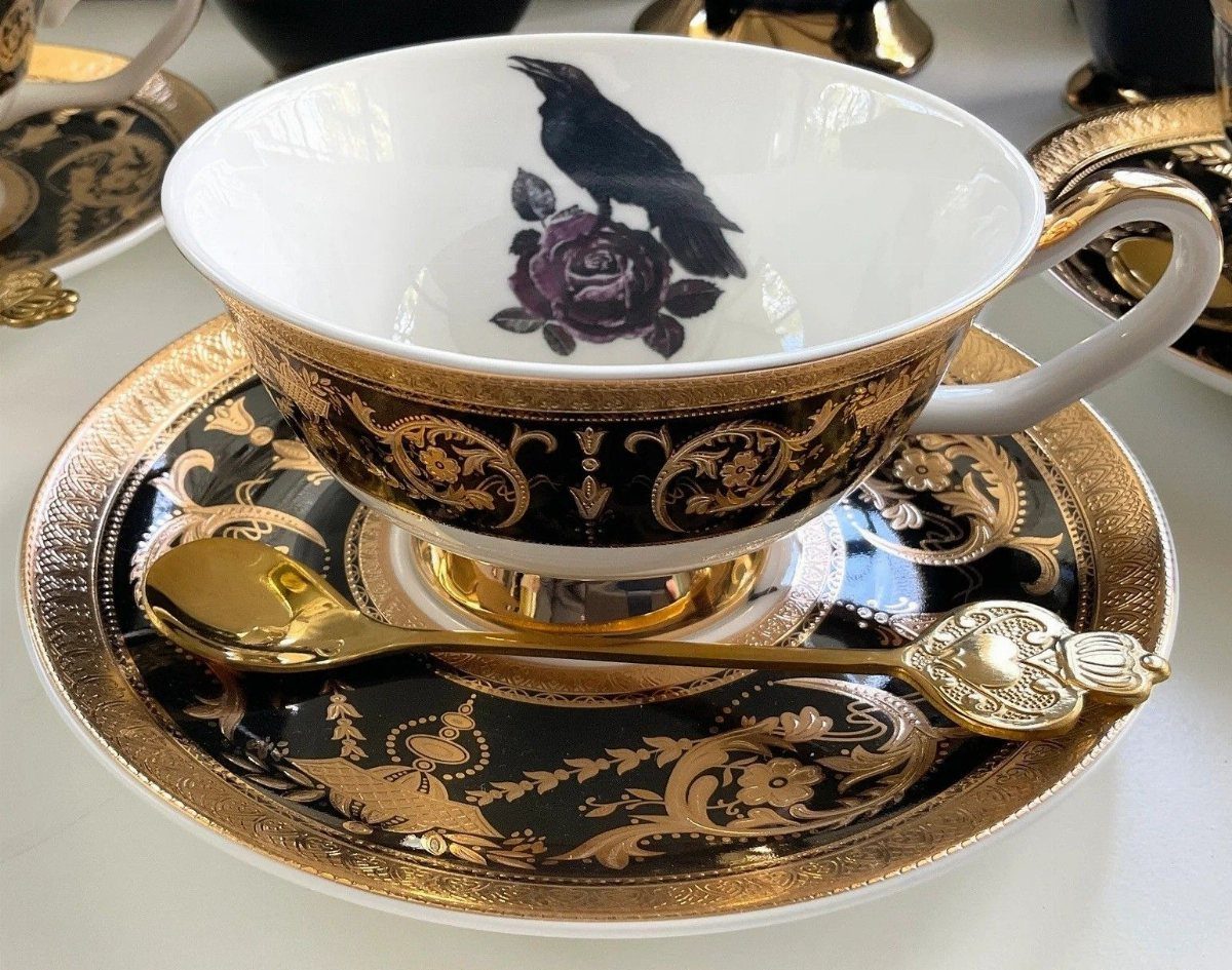 Gothic Tea Set: 24 Dark & Elegant Serving Ideas 6 Black and gold ornate teacup and saucer with raven and purple rose motif.