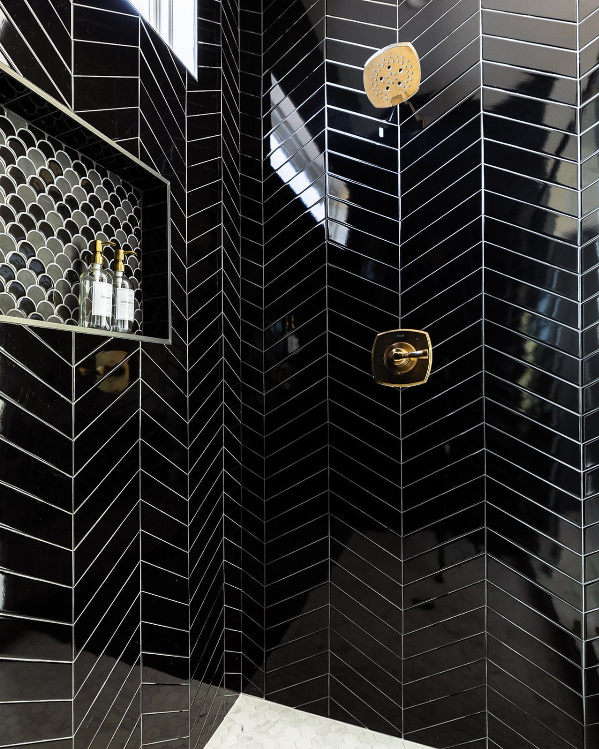 Black Mosaic Tile Bathroom: 14 Designs from Hex to Herringbone 12 Black chevron and circular mosaic tiles in a shower with gold fixtures