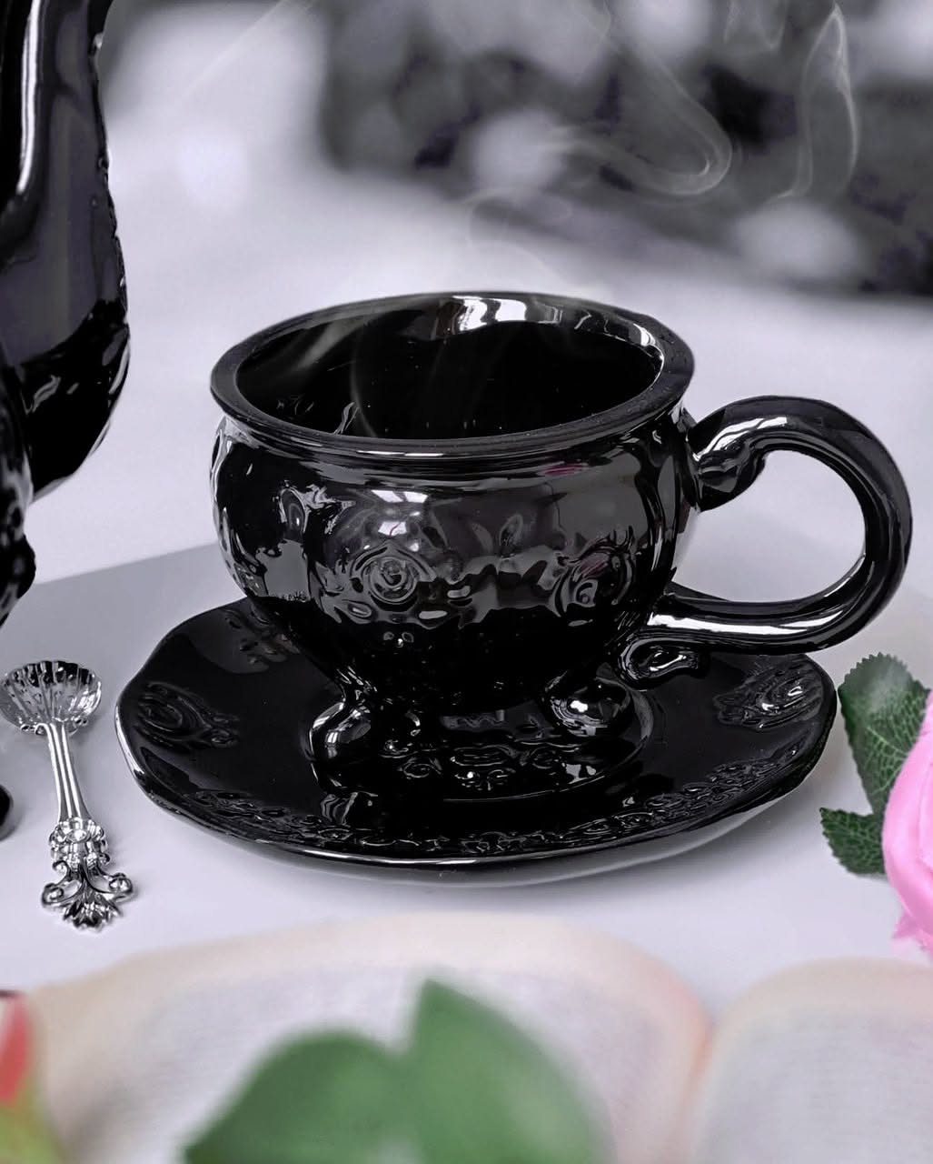 Gothic Tea Set: 24 Dark & Elegant Serving Ideas 8 Black ceramic teacup and saucer with embossed roses and a silver spoon.