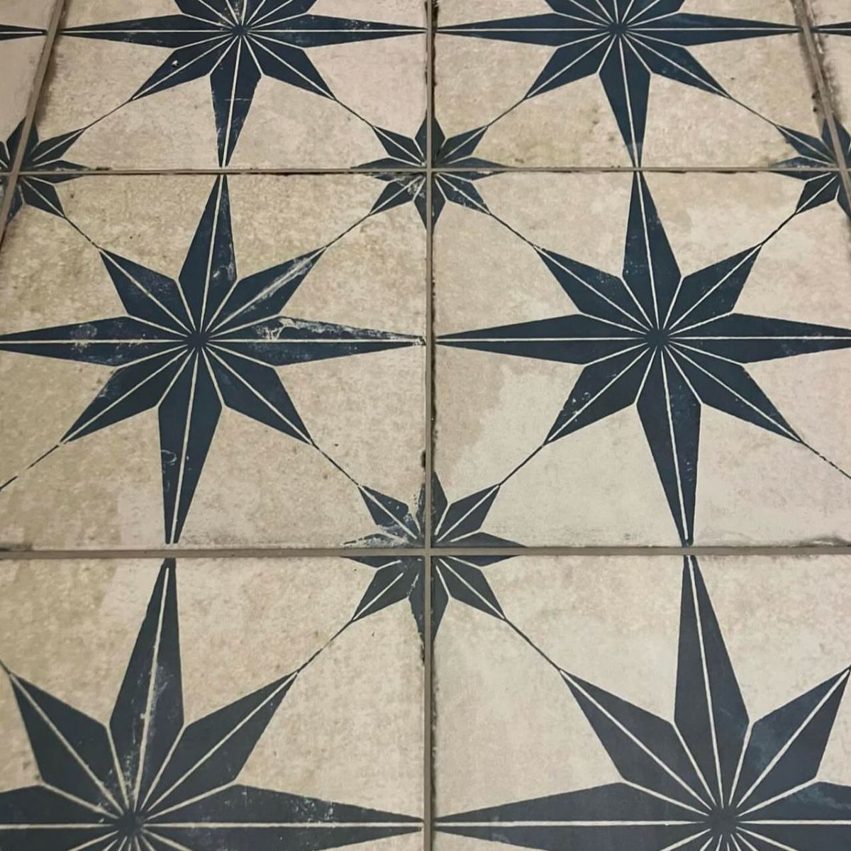 Black Mosaic Tile Bathroom: 14 Designs from Hex to Herringbone 6 White floor tiles featuring a repeating black eight-pointed star geometric pattern.