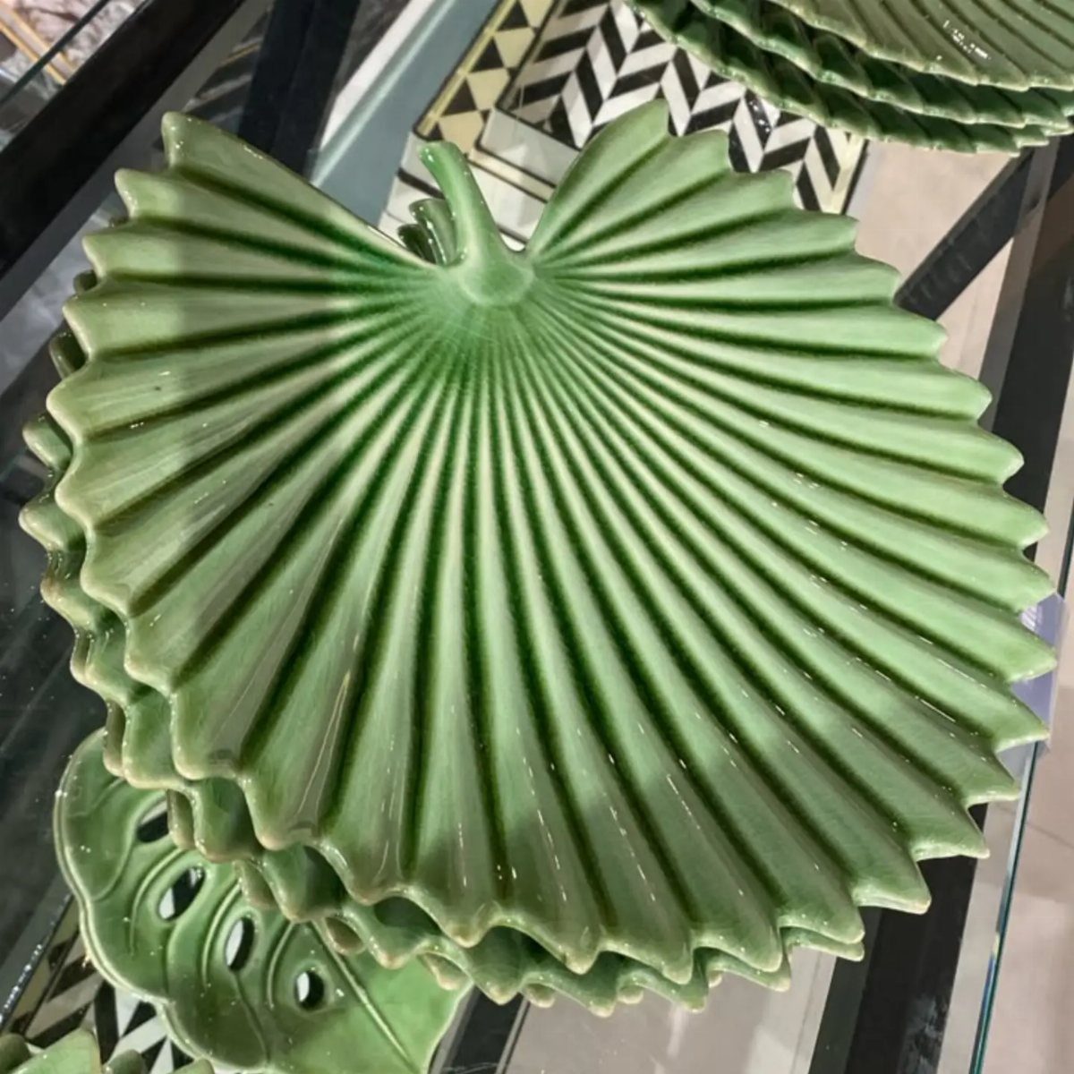 Fruit Shaped Plates in 12 Styles 2 Green ceramic plates shaped like ribbed leaves with scalloped edges on a shelf.