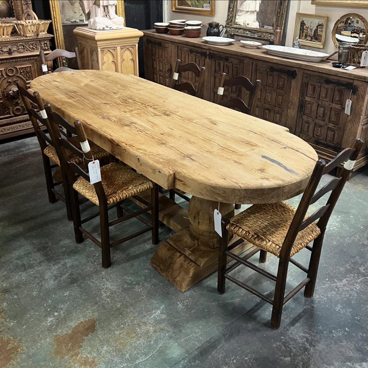 20 French Farmhouse Dining Table Ideas for Every Style 14 Oval rustic wooden trestle table with woven rush chairs in an antique shop