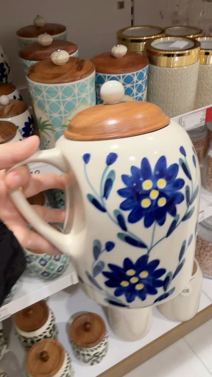 10 Kitchen Storage Container Ideas for Pantry and Fridge 7 White ceramic canister with blue flowers and a wooden lid held by a hand.