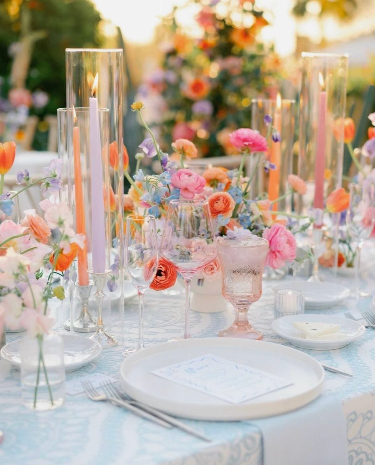 Table Decor for Round Tables: 13 Ideas to Try at Home 8 Round table set with pastel flowers, pink candles, and light blue patterned tablecloth.