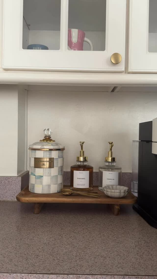 Wooden riser holding a tiled canister and syrup dispensers on a kitchen counter
