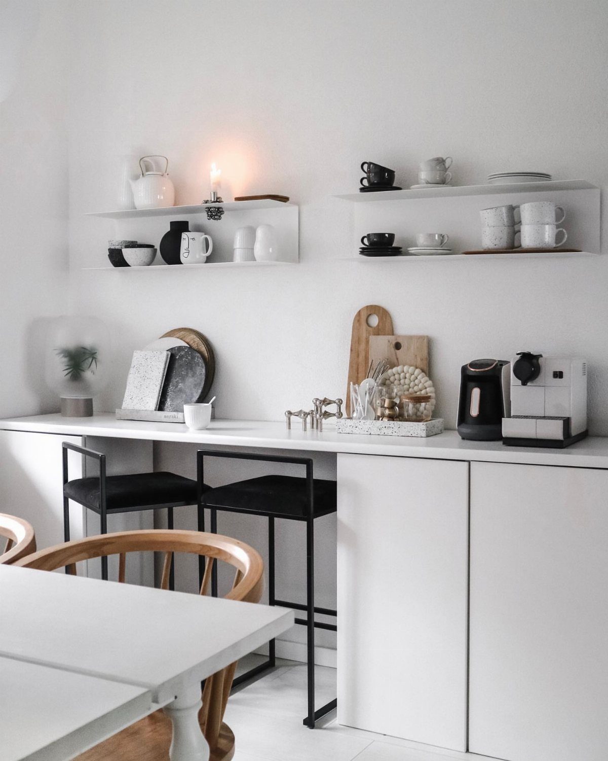 Wall Mounted Coffee Bar: 23 Stylish Space-Saving Ideas 21 White wall mounted coffee bar with floating shelves, espresso machine, and black bar stools.