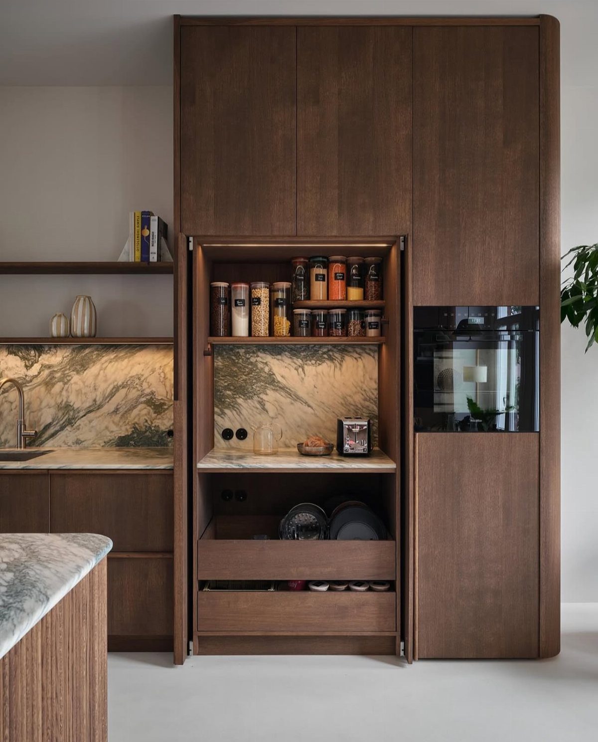 27 Small Kitchen with Fridge Ideas That Maximize Every Inch 8 Dark wood kitchen cabinetry with an open pantry featuring built-in shelves and drawers.
