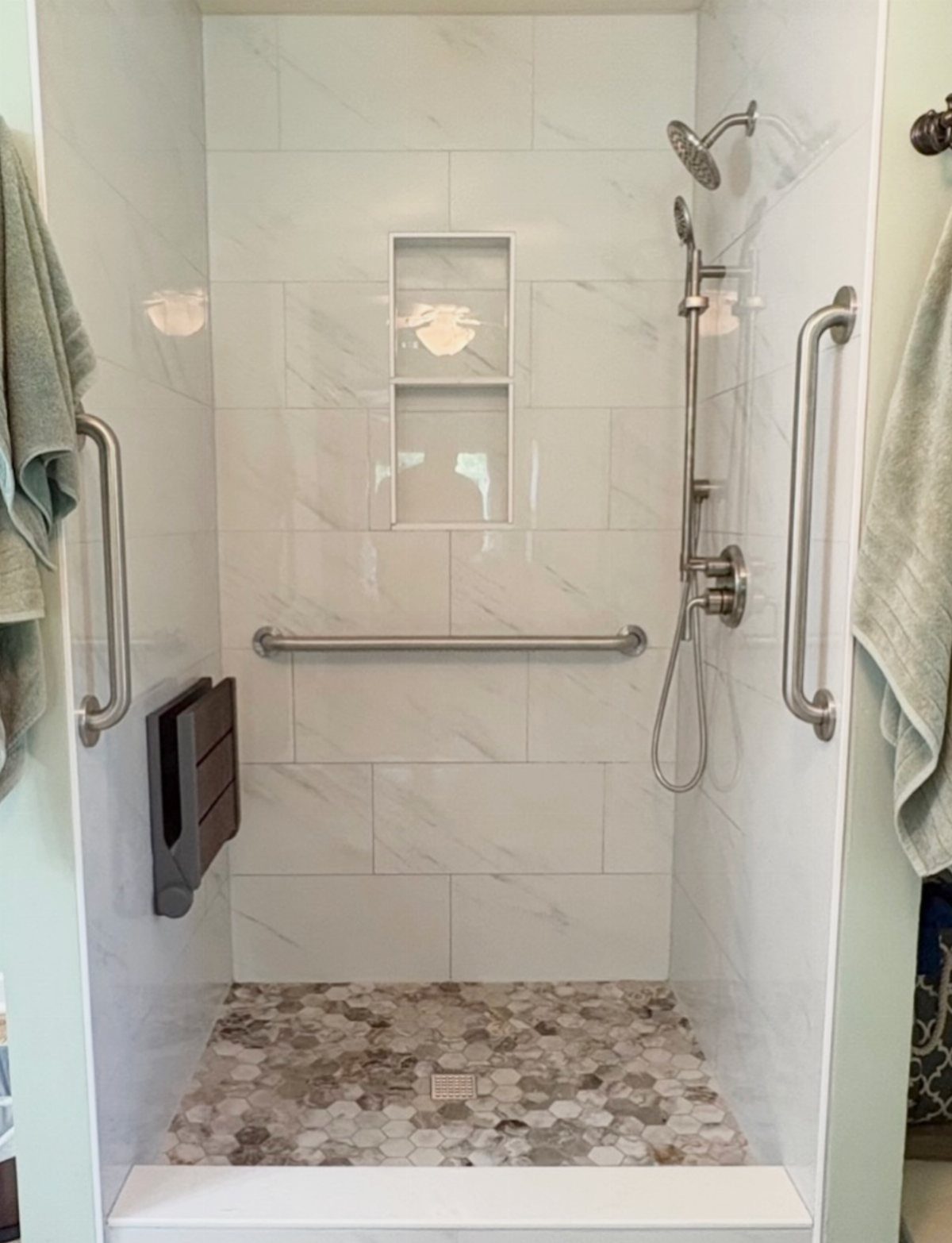 Bathroom Alcove Ideas: 29 Designs for Tubs, Showers & More 19 Walk-in shower with white marble tiles, pebble floor, and a grey fold-down bench.