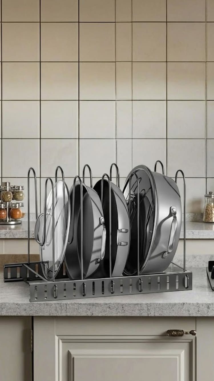 Metal storage rack holding stainless steel pot lids on a kitchen countertop.