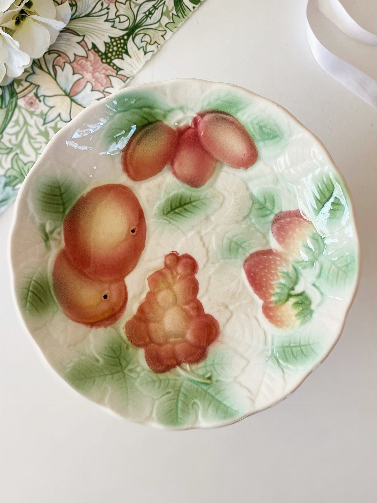 Fruit Shaped Plates in 12 Styles 13 Ceramic plate with raised relief carvings of colorful fruits and green leaves.