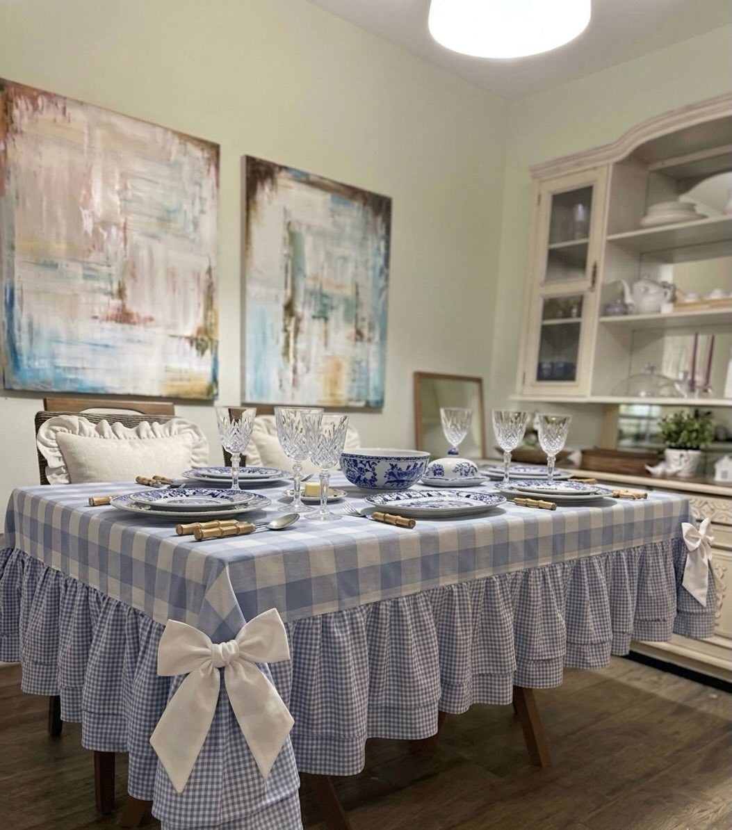 Blue and white gingham checkered tablecloth with ruffles and bows on a dining table.