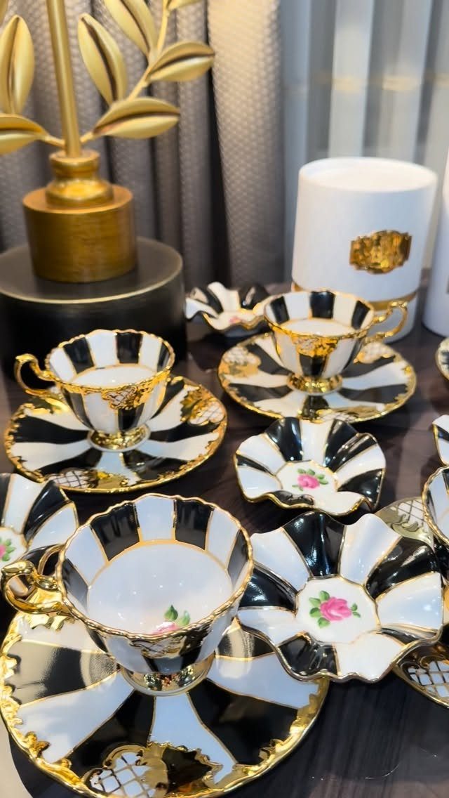 Gothic Tea Set: 24 Dark & Elegant Serving Ideas 16 Black and white porcelain tea set with gold gilded rims and pink floral patterns.