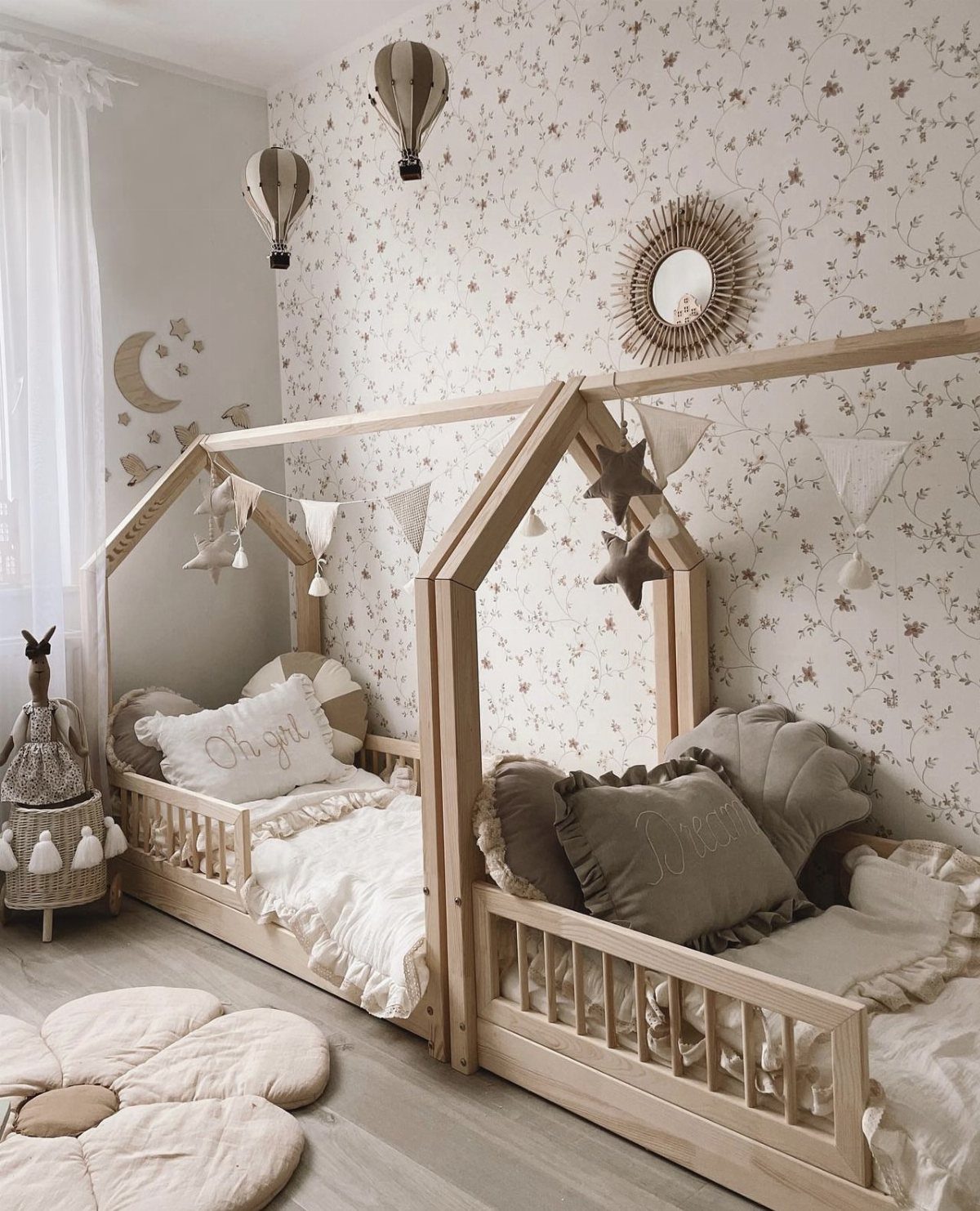 8 Ideas for a Bedroom with 2 Beds That Save Space 8 Two house-shaped wooden beds in a children's bedroom with floral wallpaper and beige decor.