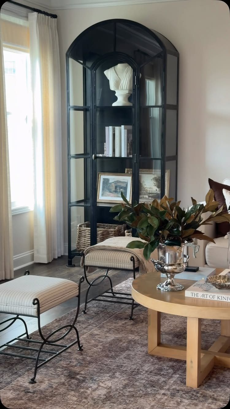 27 Vibey Living Room Aesthetic Ideas Worth Copying 14 Elegant living room with black arched cabinet, wooden coffee table, and neutral upholstered stools.