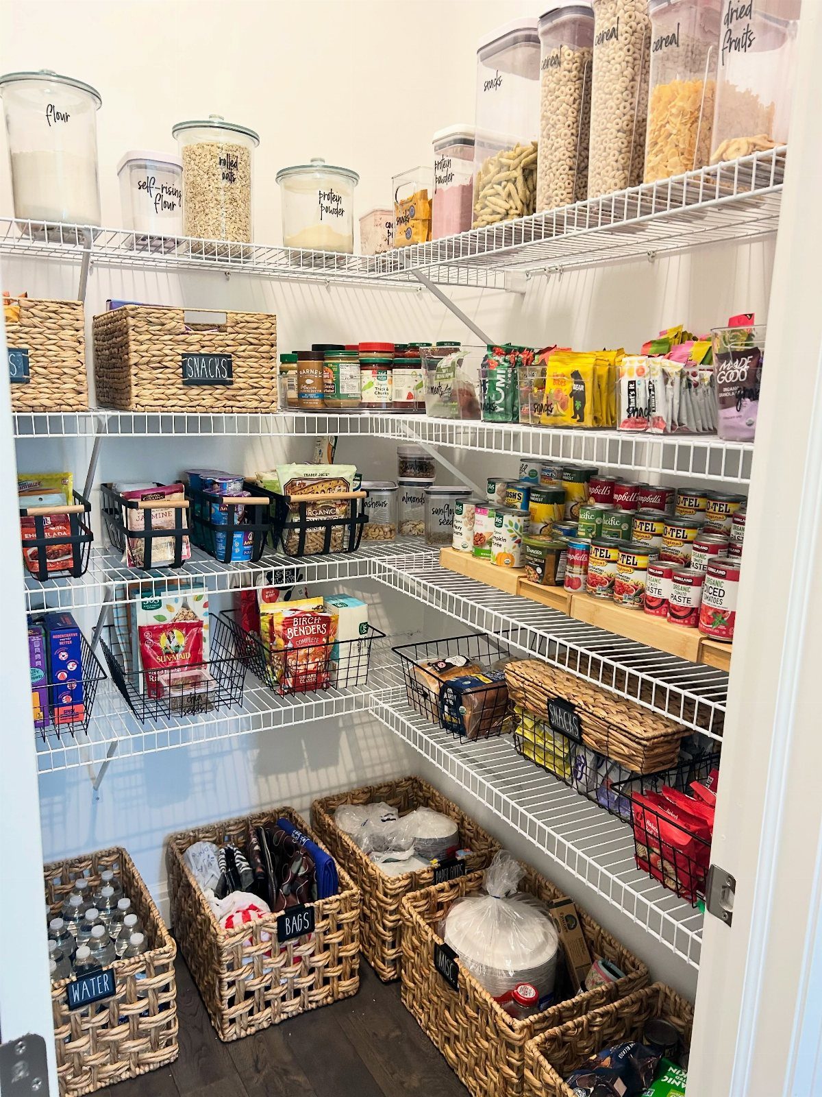 Organized pantry with white wire shelves and woven baskets on the floor.