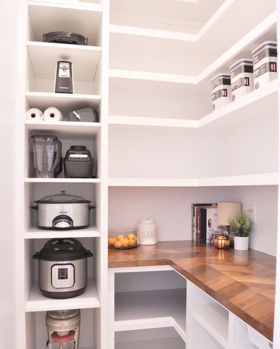 White kitchen pantry shelves with organized appliances and a wooden butcher block countertop.