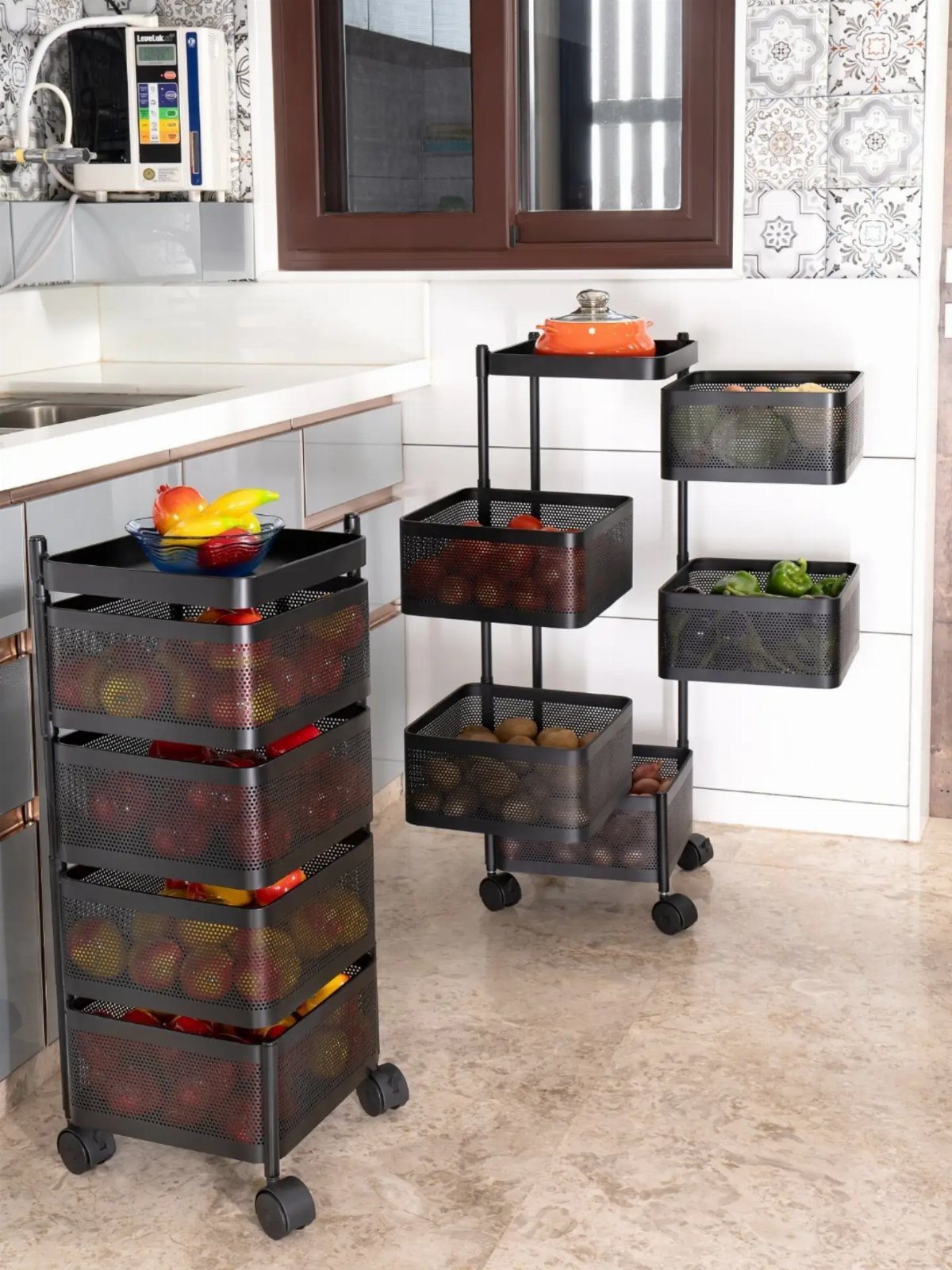 Black metal mesh rolling storage carts filled with colorful vegetables in a bright kitchen.