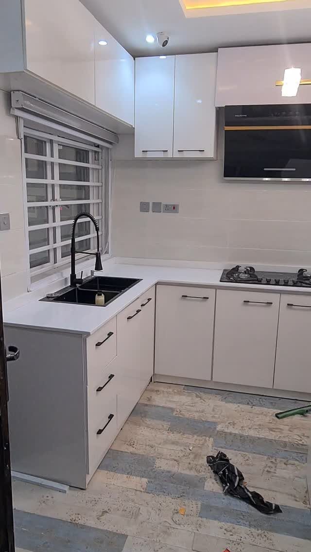 32 Simply Kitchen Design Ideas for a Clean, Modern Space 8 White L-shaped kitchen with flat-panel cabinets, black sink, and light tiled flooring.