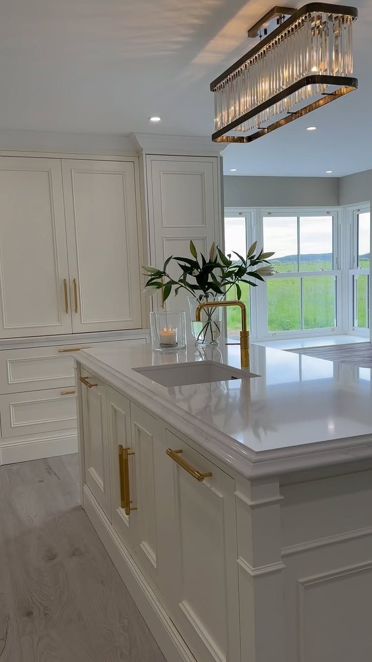 32 Simply Kitchen Design Ideas for a Clean, Modern Space 31 White kitchen island with gold hardware and large windows overlooking a green field.