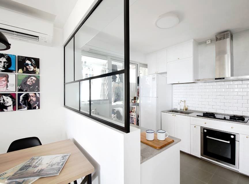 Low white wall with black glass partition separating a white kitchen from dining area