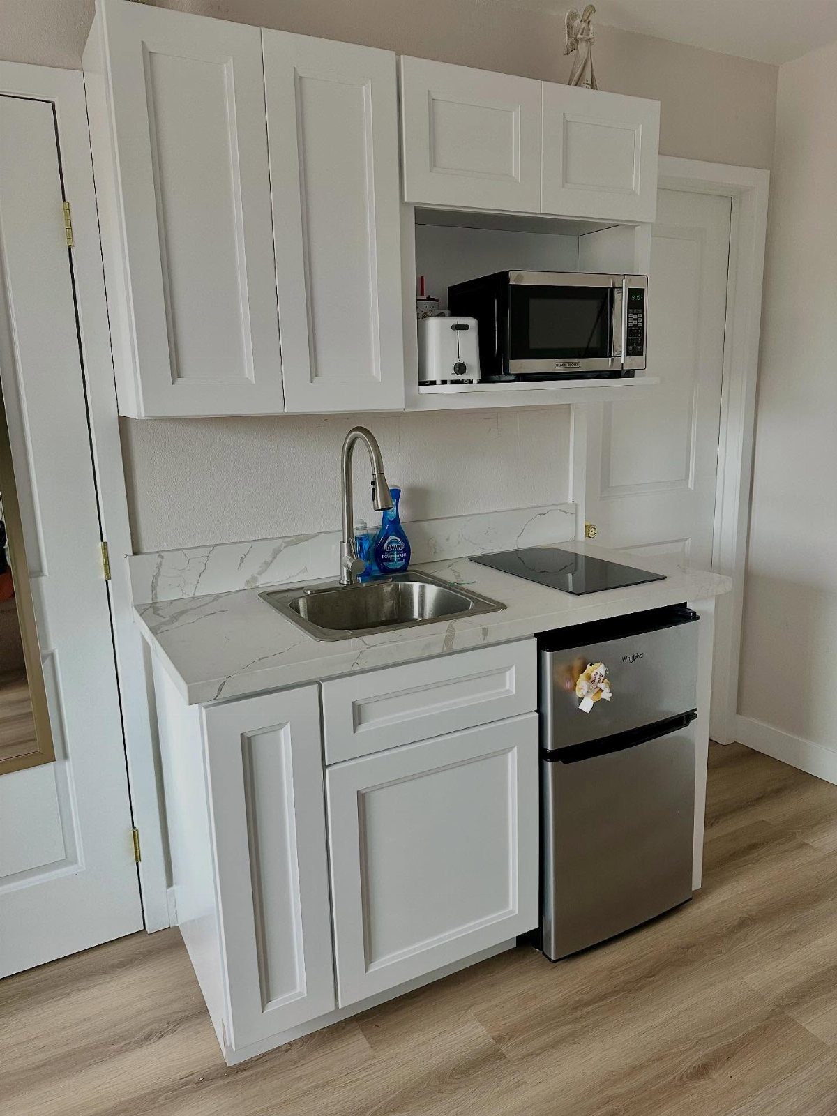 27 Small Kitchen with Fridge Ideas That Maximize Every Inch 23 Small white kitchenette with marble countertop, stainless steel sink, and compact silver mini-fridge.