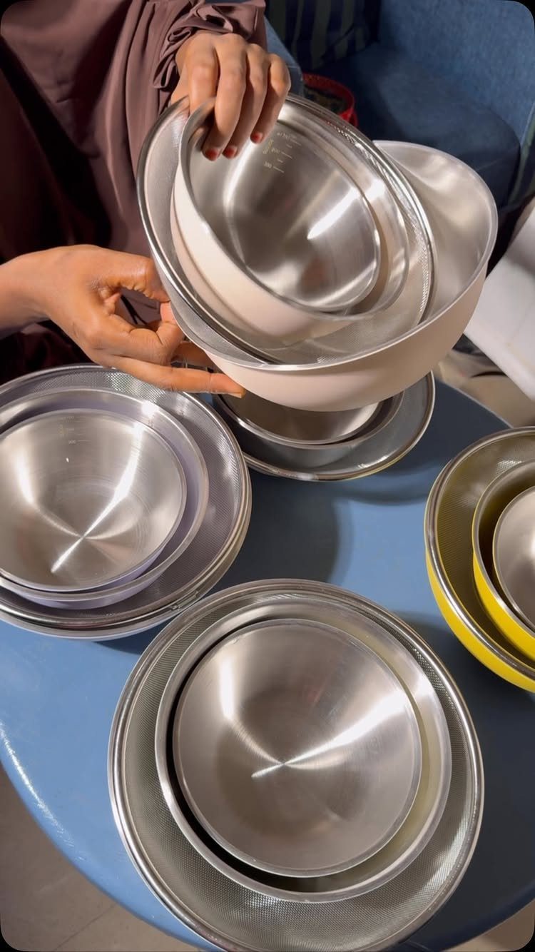 Small Kitchen Essentials: 13 Tools That Actually Matter 4 Nested stainless steel and white mixing bowls held by hands over a blue table.