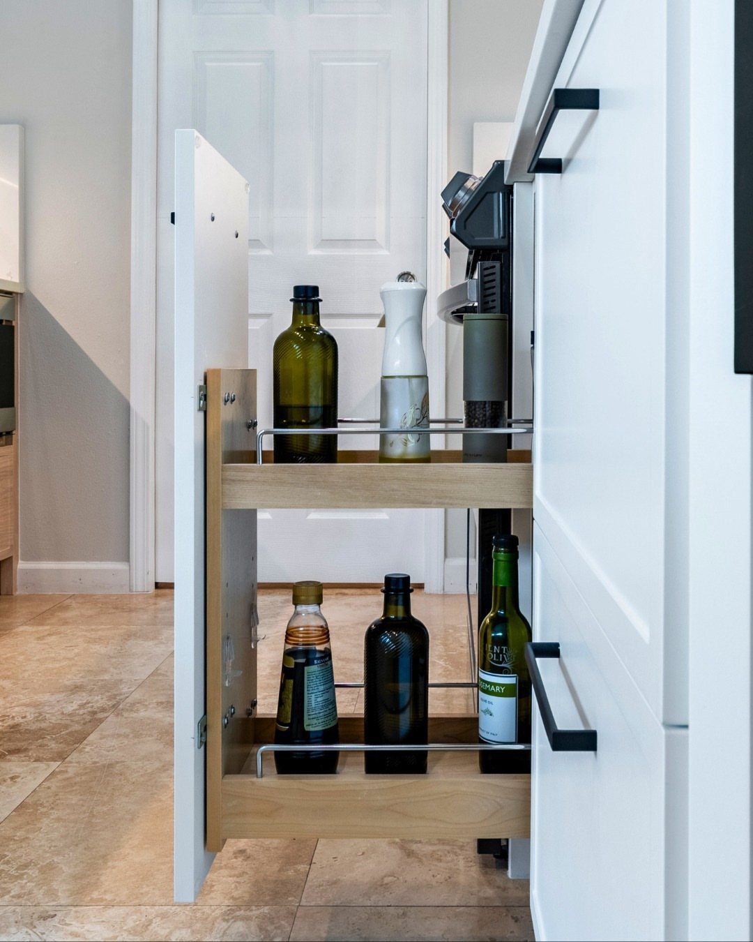 26 Pull Out Drawer Kitchen Ideas That Save Space 4 Narrow vertical pull-out kitchen cabinet drawer holding various bottles of oil and vinegar.
