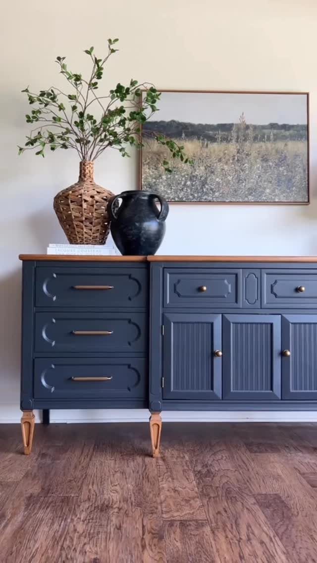 Navy blue refinished sideboard with wooden top and gold hardware against a white wall.
