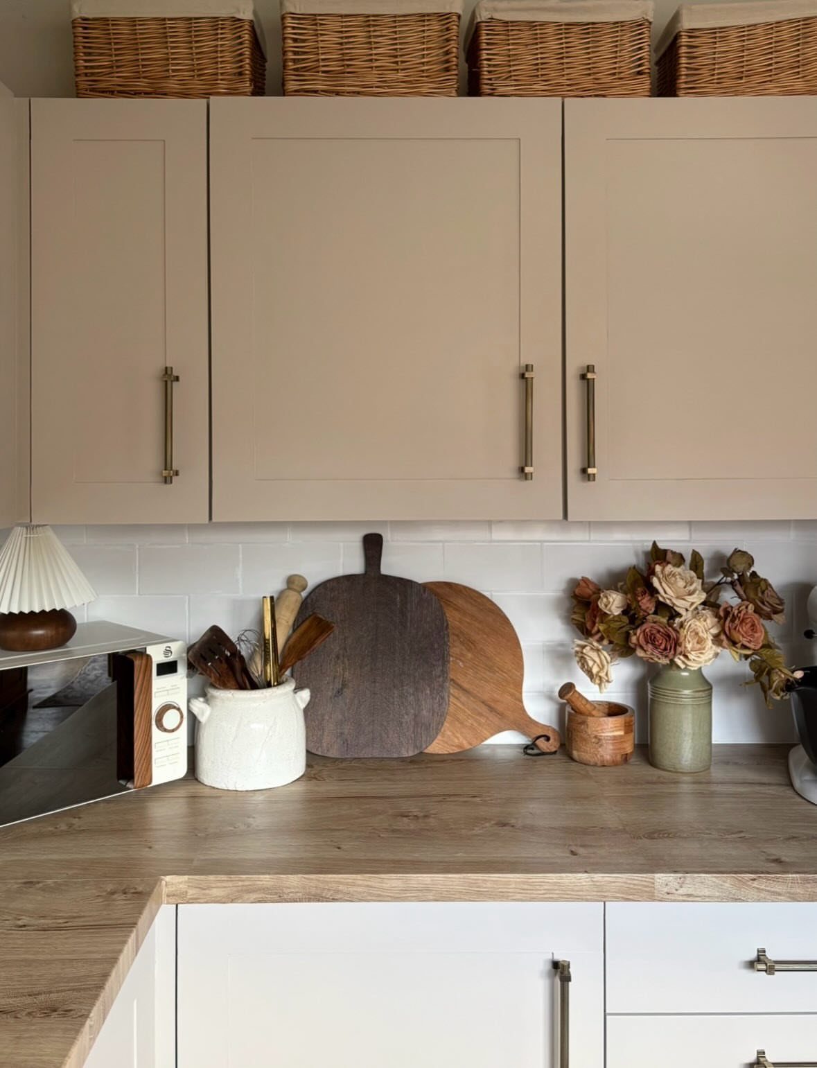 Wicker baskets with fabric liners stored on top of beige kitchen cabinets.