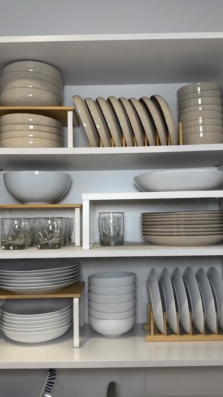 17 Ways to Organize Kitchen Tools (With Photos for Each) 17 White ceramic plates and bowls organized on minimalist white kitchen shelves.