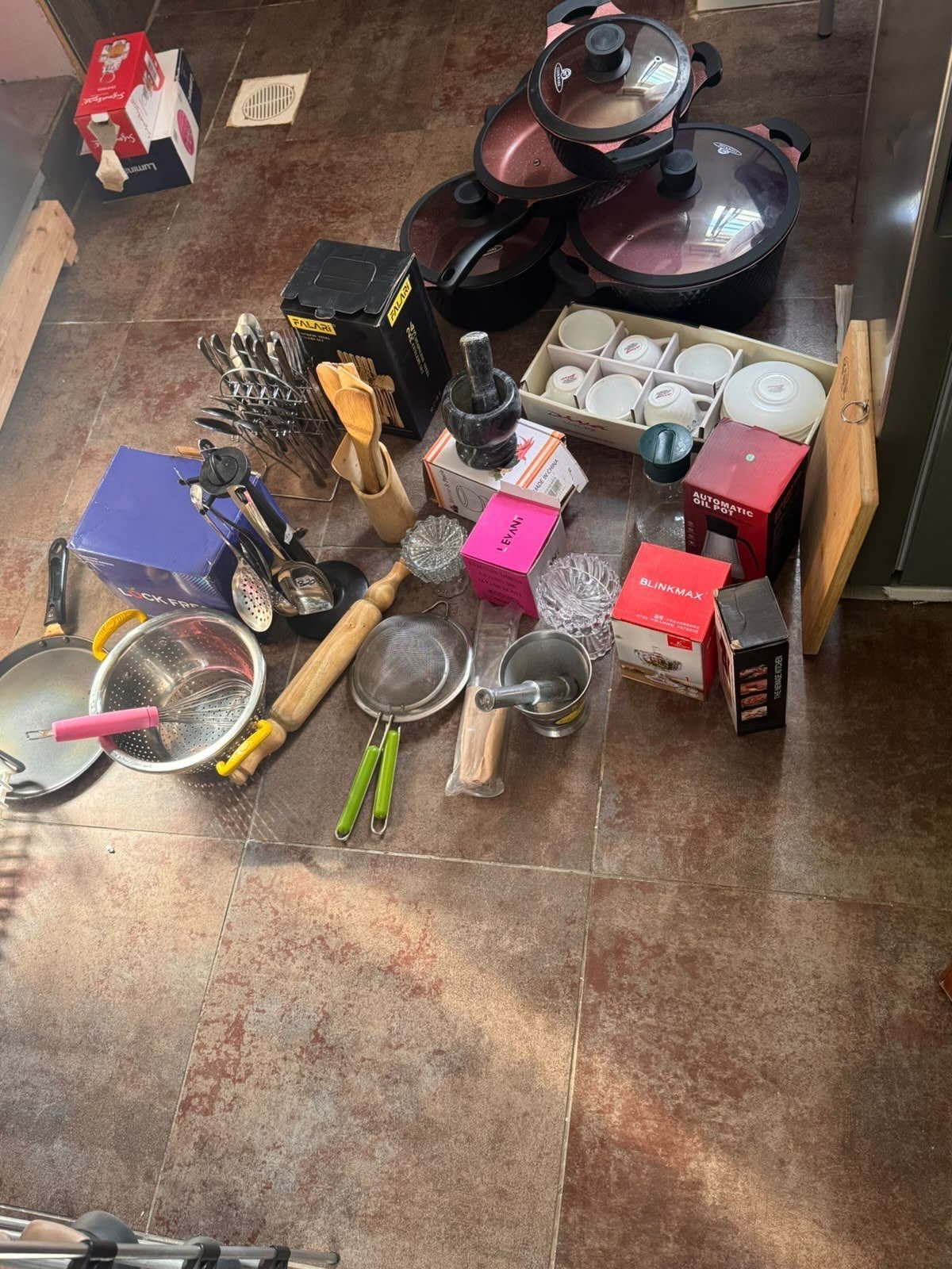 17 Ways to Organize Kitchen Tools (With Photos for Each) 9 Kitchen tools and pots scattered on a brown tiled floor for sorting and organizing.
