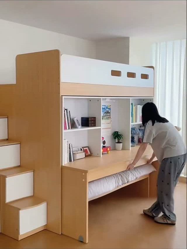 12 Space Saving Furniture Ideas That Actually Work 10 Person pulling out a trundle bed from under a wooden bunk bed with shelving.