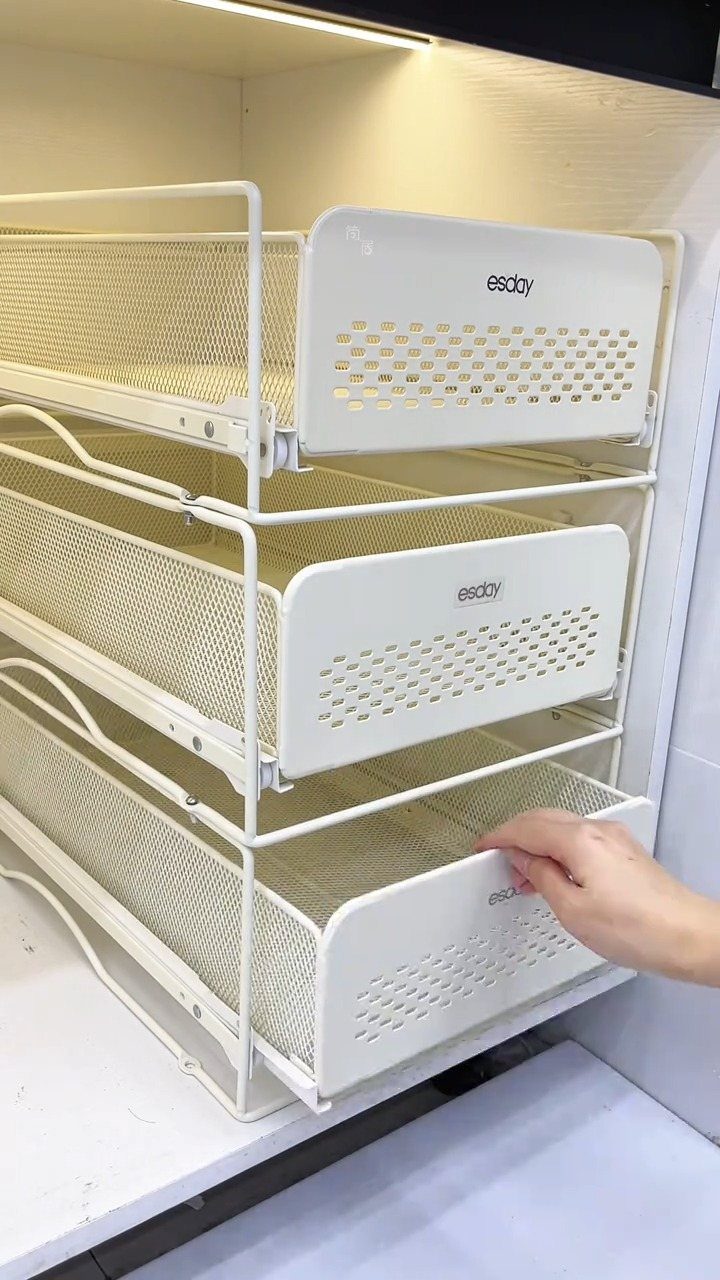 17 Ways to Organize Kitchen Tools (With Photos for Each) 11 White mesh pull-out storage drawers stacked inside a clean white kitchen cabinet.