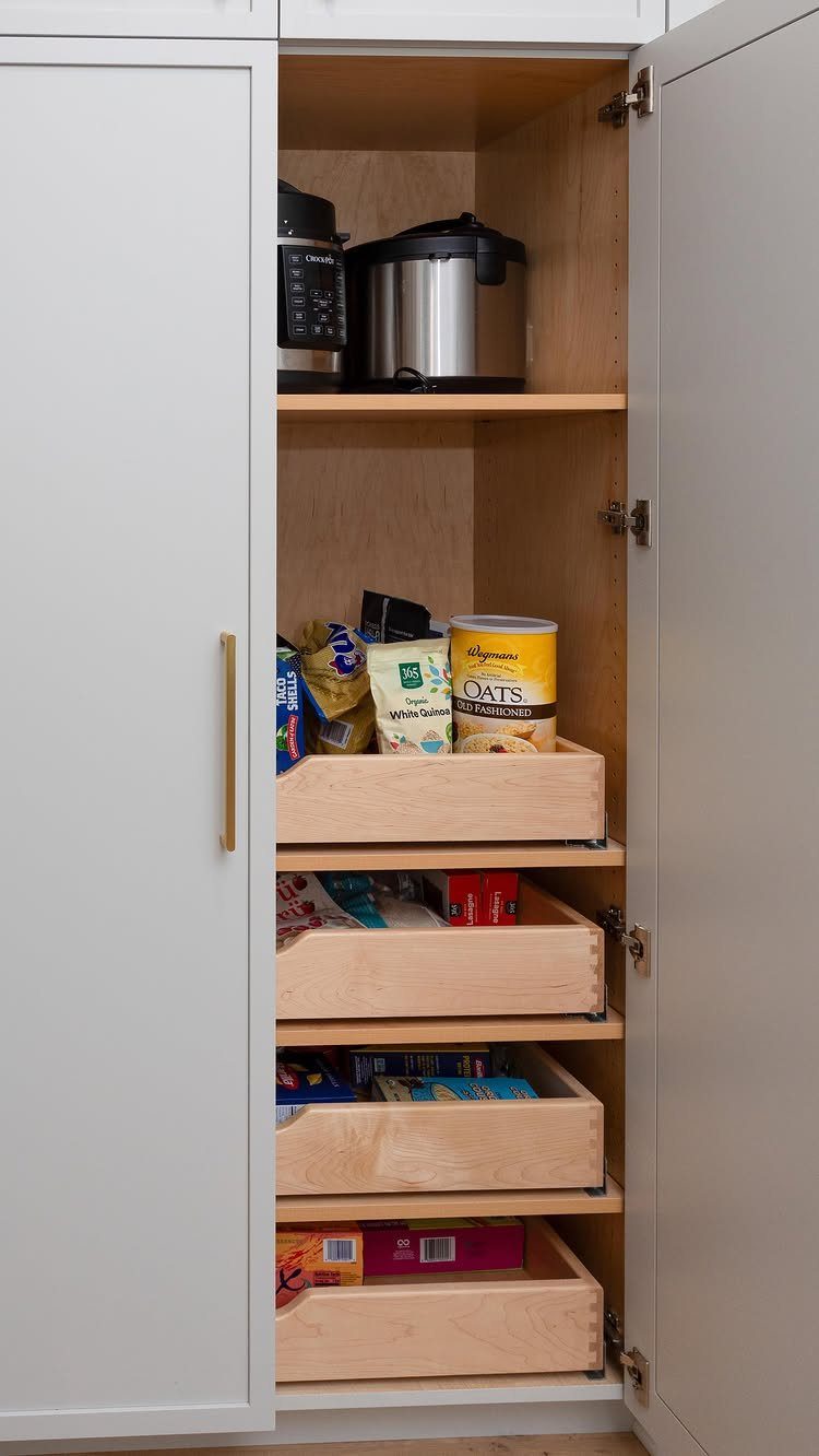 Kitchen Without Upper Cabinets: 13 Ideas That Work 12 White pantry cabinet with open door showing pull-out wooden drawers filled with food.