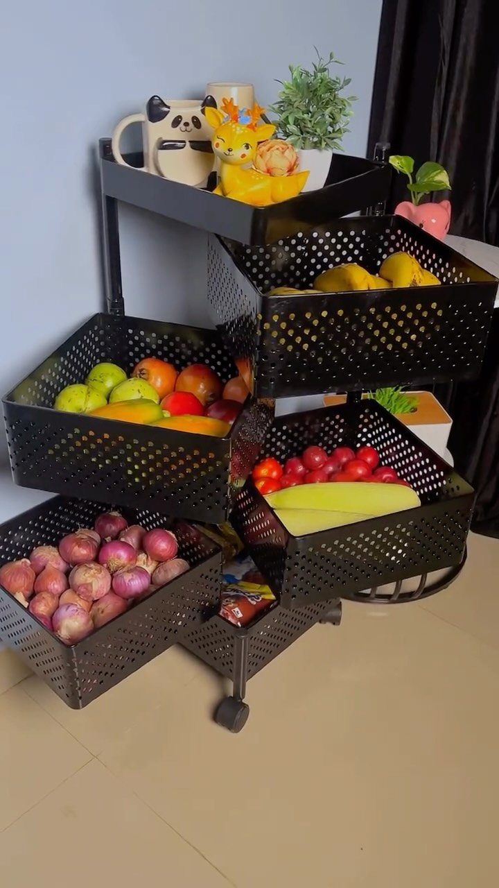 Black metal rolling storage rack with perforated baskets filled with fresh produce and decor.