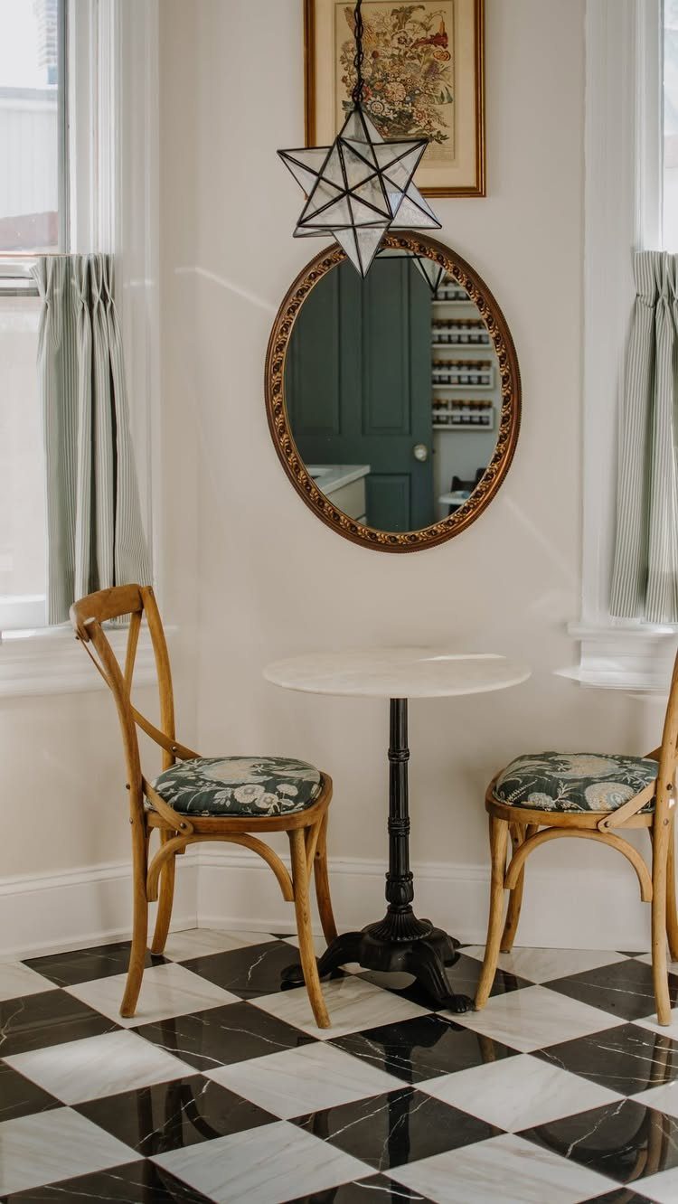 20 French Farmhouse Dining Table Ideas for Every Style 21 Small round white bistro table with wooden cross-back chairs on checkered marble floor.