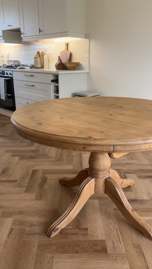 20 French Farmhouse Dining Table Ideas for Every Style 19 Round wooden pedestal dining table on a herringbone floor in a white kitchen.