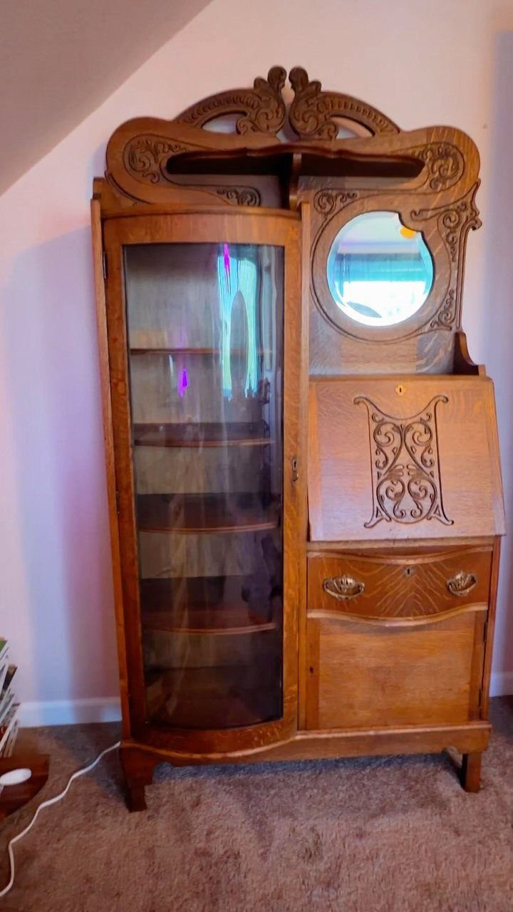 Vintage wooden secretary desk with a curved glass hutch and circular mirror.