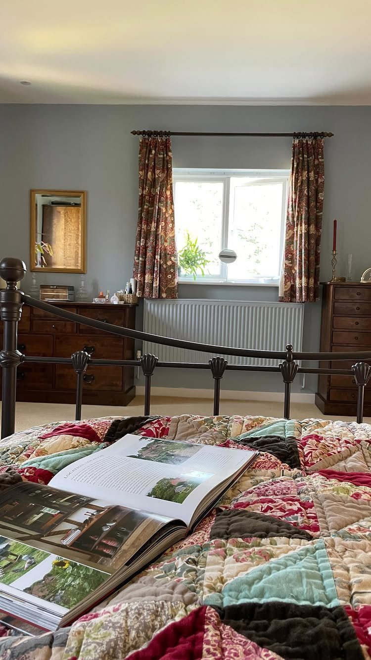 Floral curtains on a short bedroom window above a white radiator and bed.