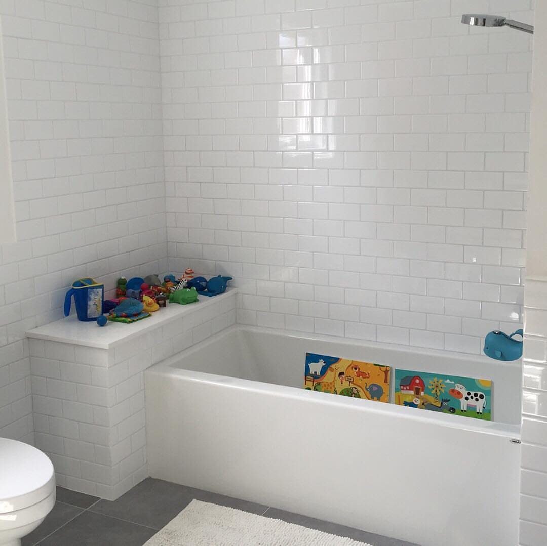 Bathroom Alcove Ideas: 29 Designs for Tubs, Showers & More 20 White skirted bathtub against white subway tile walls with toys on a ledge