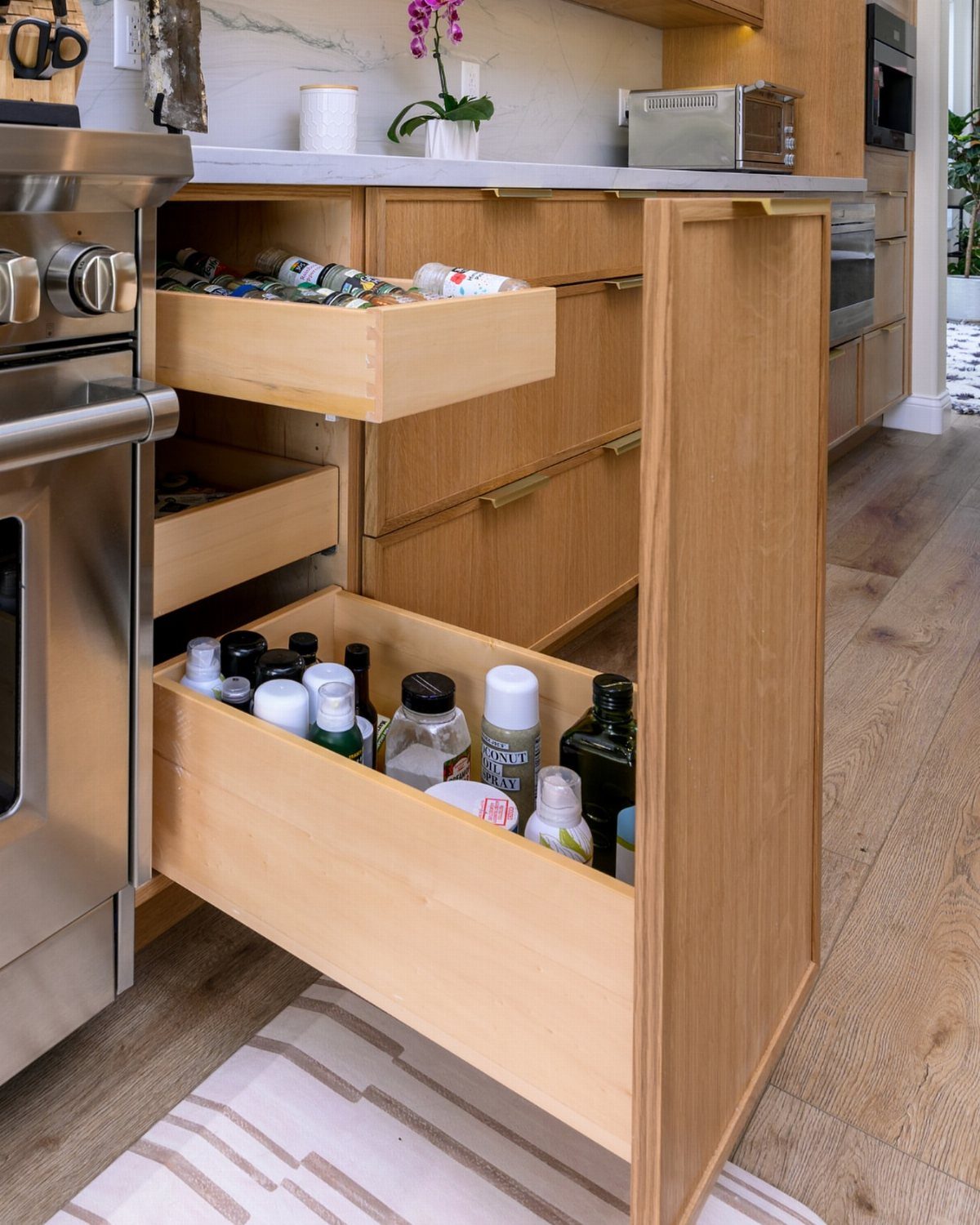26 Pull Out Drawer Kitchen Ideas That Save Space 15 Light wood kitchen cabinet with a pull-out drawer filled with spice jars.