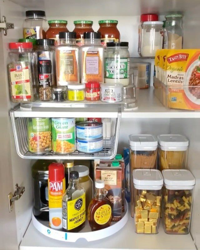 Organized small white pantry with glass jars, plastic containers, and a rotating lazy Susan.