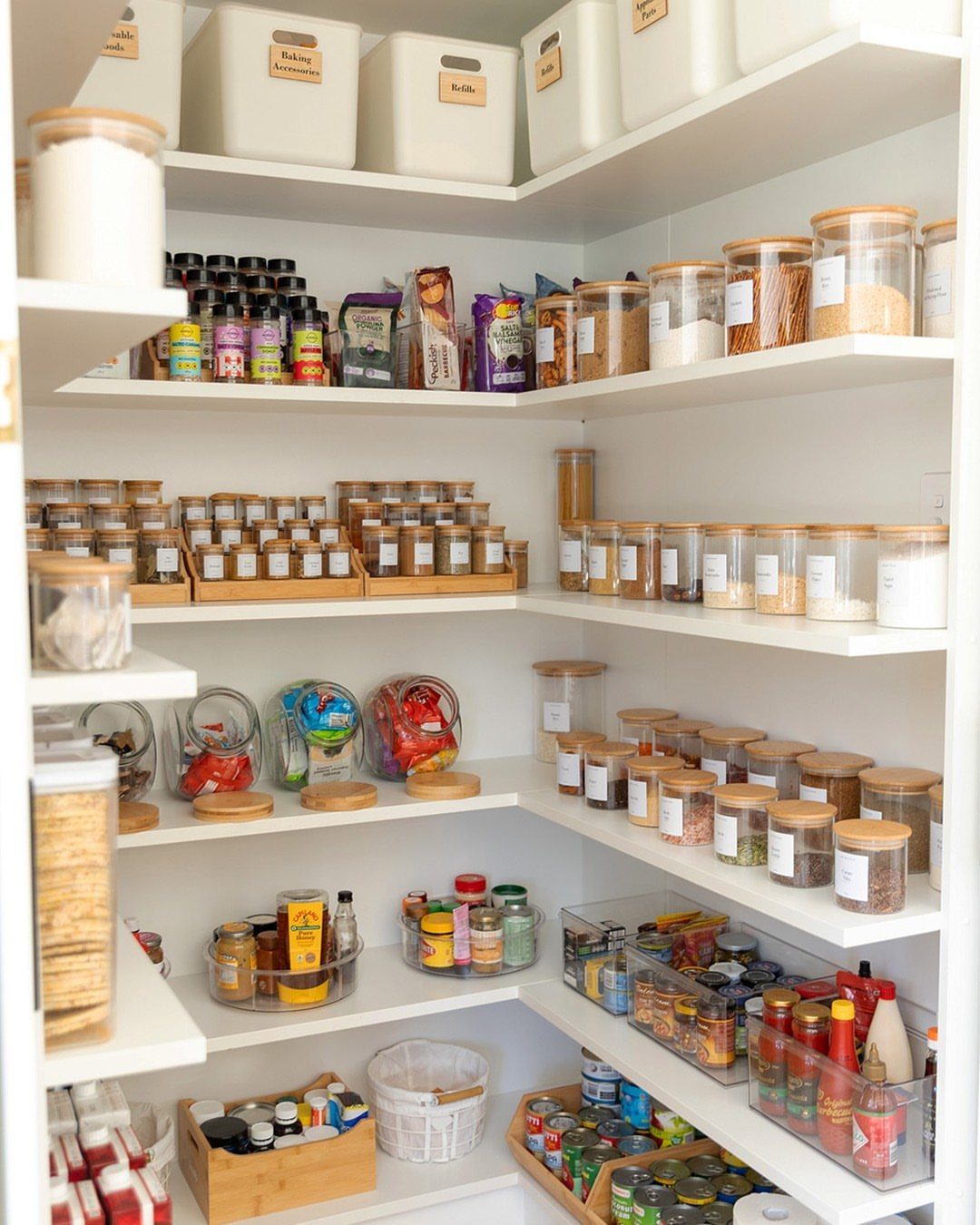 Organized pantry shelves with clear containers, spice jars, and bins for food storage.